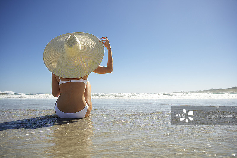 坐在海滩上戴太阳帽的女人图片素材