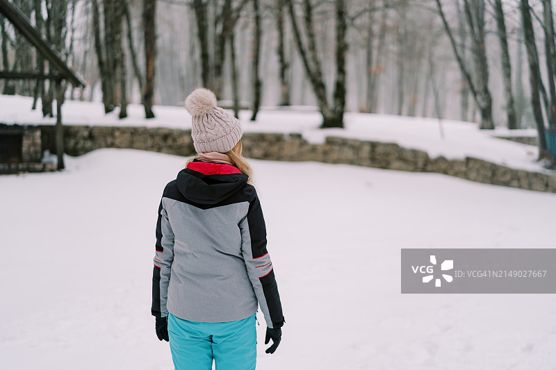 一个女人站在白雪皑皑的森林里，望向远方图片素材