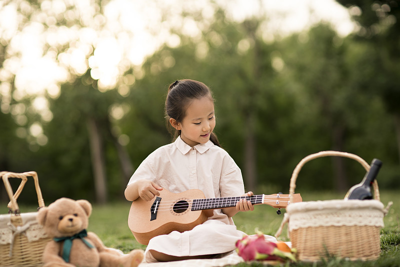 小女孩在草地上彈吉他圖片下載