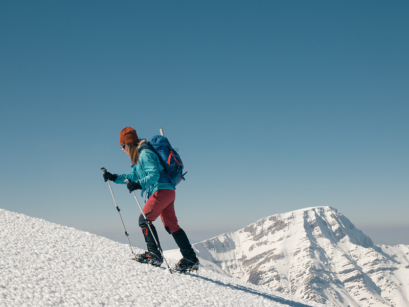 冬季，女性攀登者在高海拔的山峰上行走圖片素材