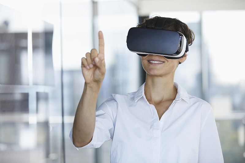 女商人戴著虛擬現實眼鏡在辦公室舉起手指圖片素材