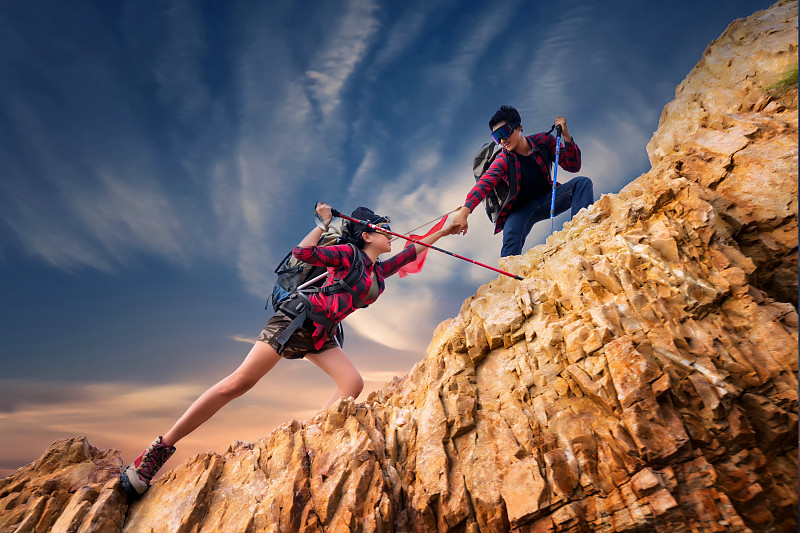 亞洲夫婦徒步登山，幫助登山。團隊和領導的概念。度假，露營，旅行和放松的概念。圖片素材