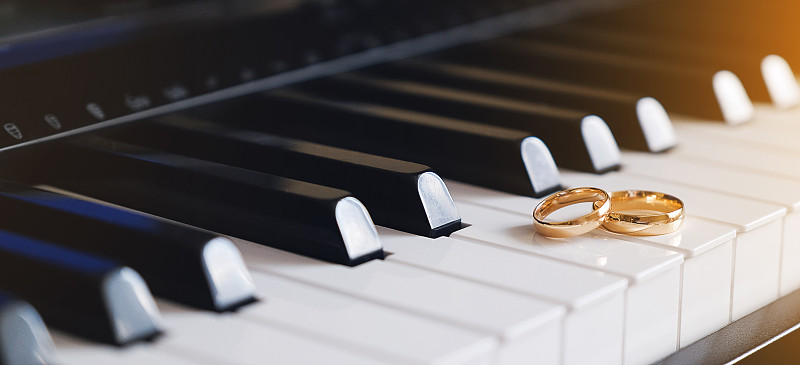 鋼琴琴鍵上放著結婚金戒指。圖片素材