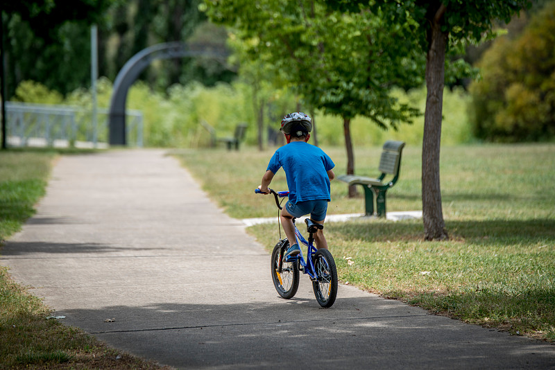 在公園里騎自行車的男孩的后視圖圖片素材