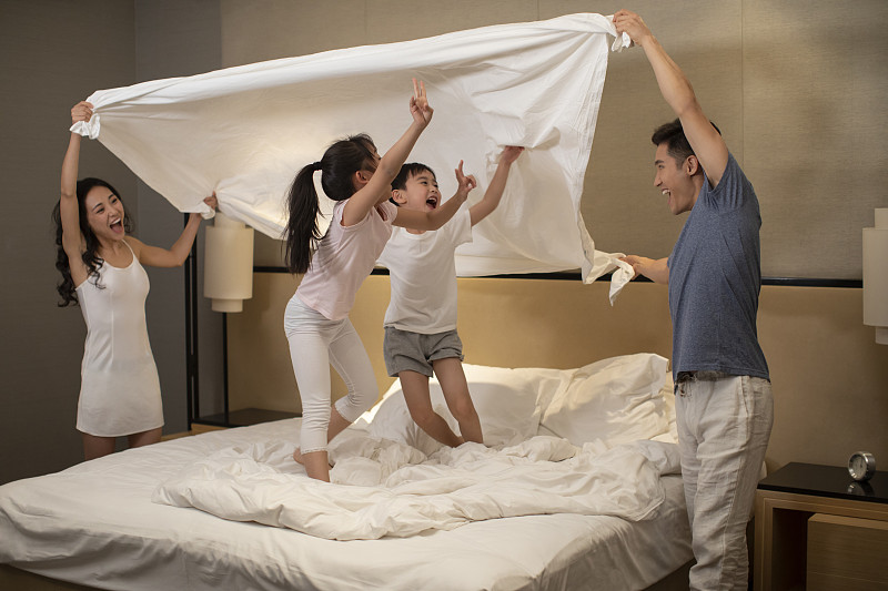 快乐的年轻家庭在卧室玩耍图片下载