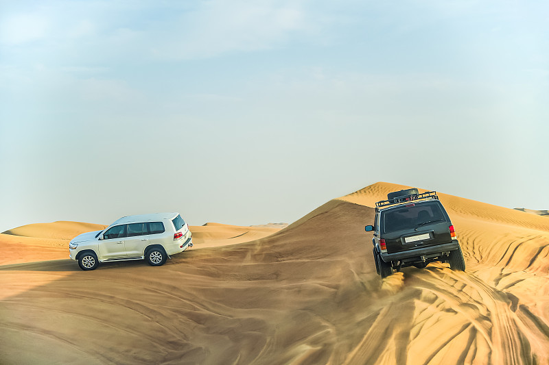 夏季阿联酋迪拜旅游景点沙漠冲沙行程中行驶的车辆图片下载