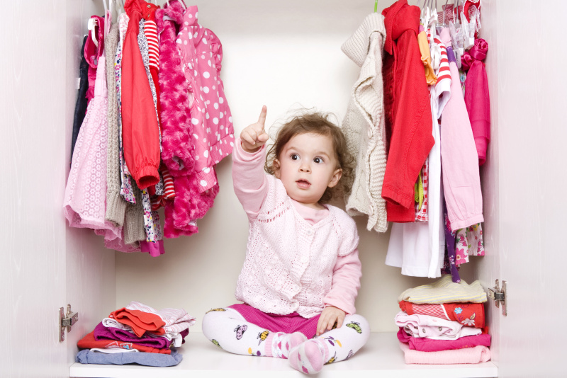 小女孩坐在衣柜里，穿著紅色和粉色的衣服圖片下載