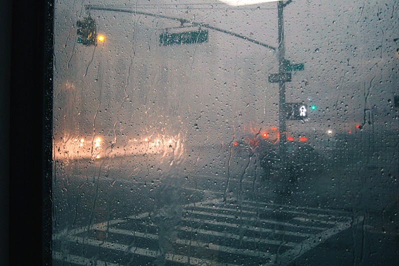 在城市街道背景玻璃上的雨滴特寫圖片素材