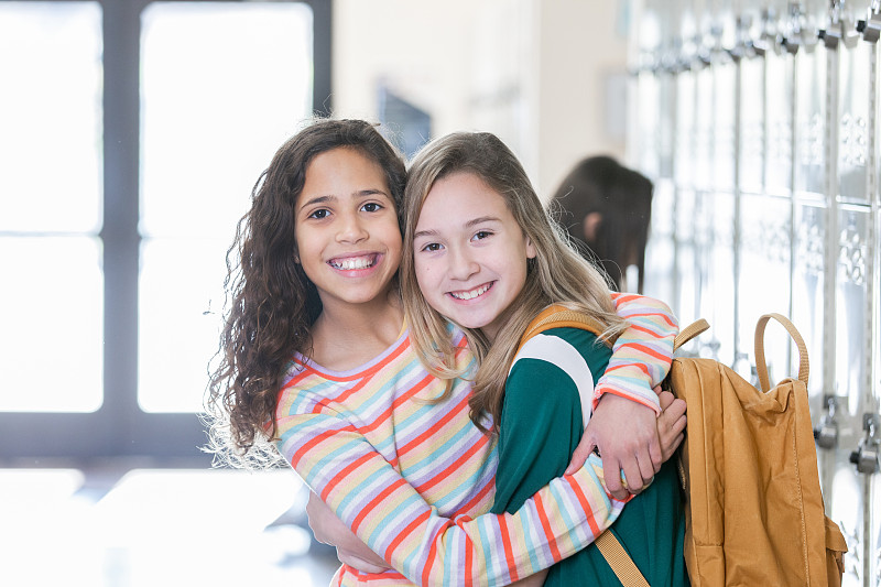 小學女生在學校走廊擁抱朋友圖片素材