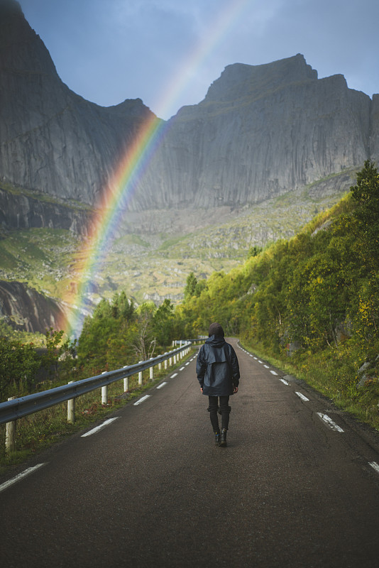 挪威，羅浮敦群島，一個人走在山路上，背景是山和彩虹圖片素材