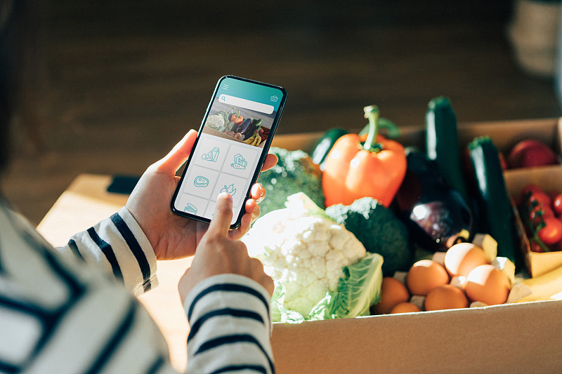 年輕女子用智能手機在網上訂購食品雜貨圖片素材