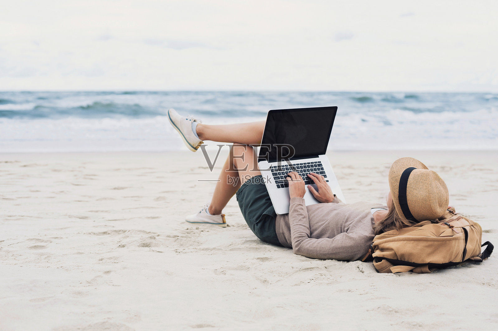 年輕女子在海灘上用筆記本電腦照片攝影圖片