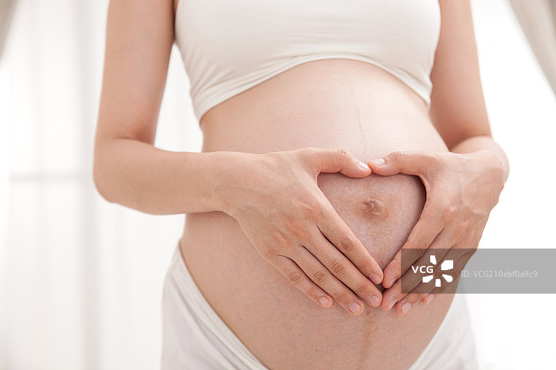 孕妇在肚子上做心型的手势图片素材