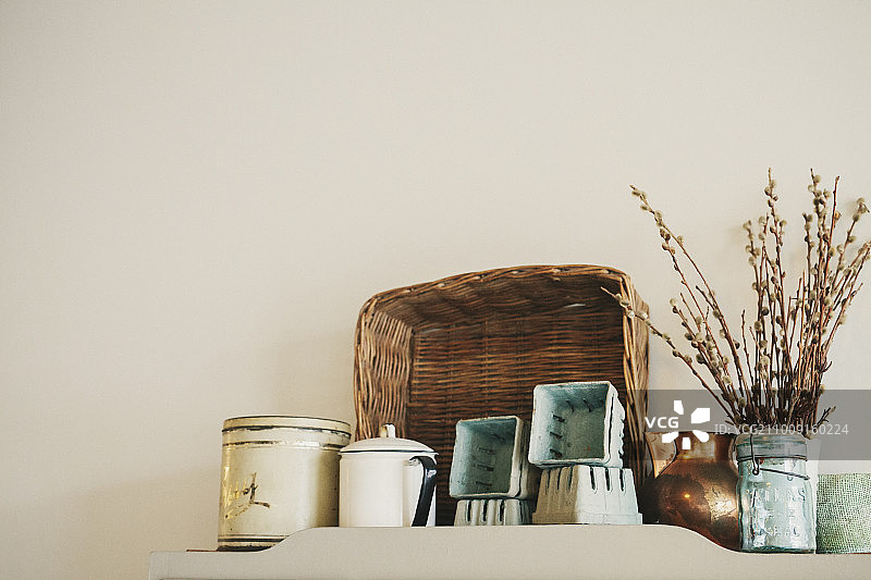 一组搪瓷和陶制的水壶和马克杯，放在架子上，上面有一个篮子。图片素材