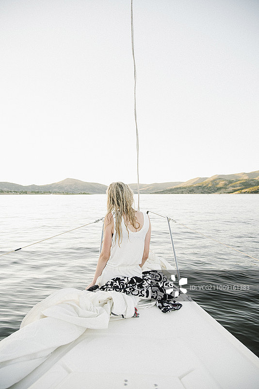 金发少女坐在帆船上。图片素材