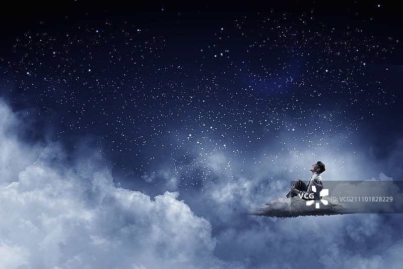 夜空中的商人。西装革履的商人独自坐在云上望着月亮图片素材