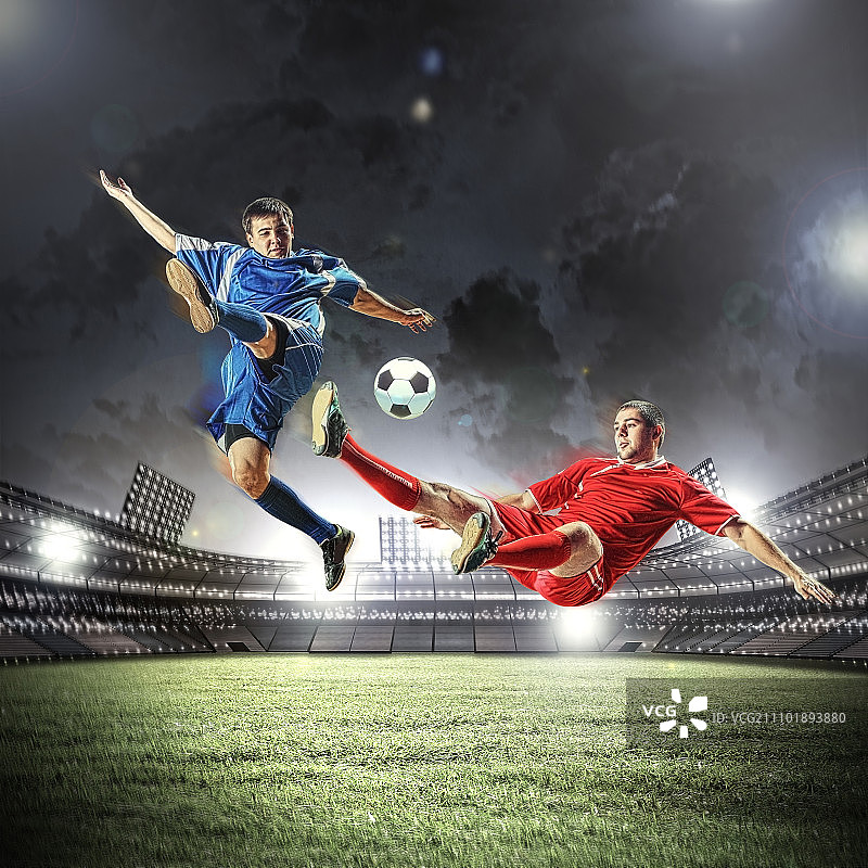 两个足球运动员击球。两名足球运动员在体育场上跳起击球图片素材