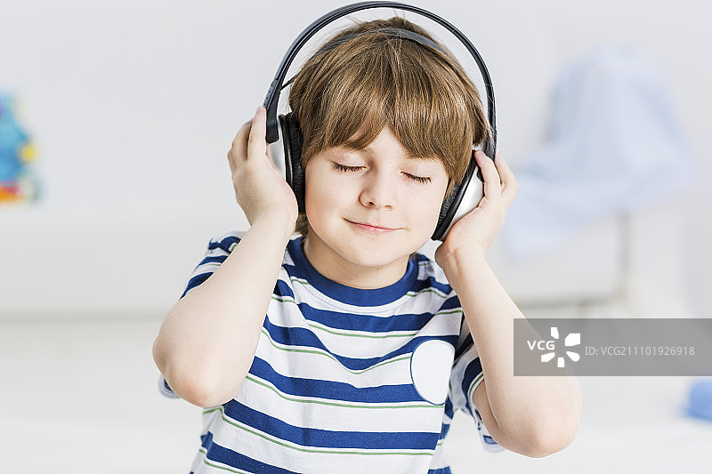 可爱的男孩戴着耳机，享受音乐。我喜欢这首歌图片素材