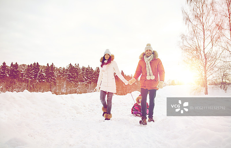 为人父母，时尚，季节和人的概念-幸福的家庭与孩子在冬季户外雪橇行走图片素材