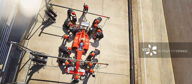 高架维修站工作人员在维修站车道上为一级方程式赛车工作图片素材