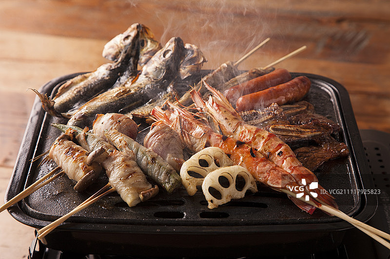 铁板上正在烤制的海鲜，肉类以及蔬菜图片素材
