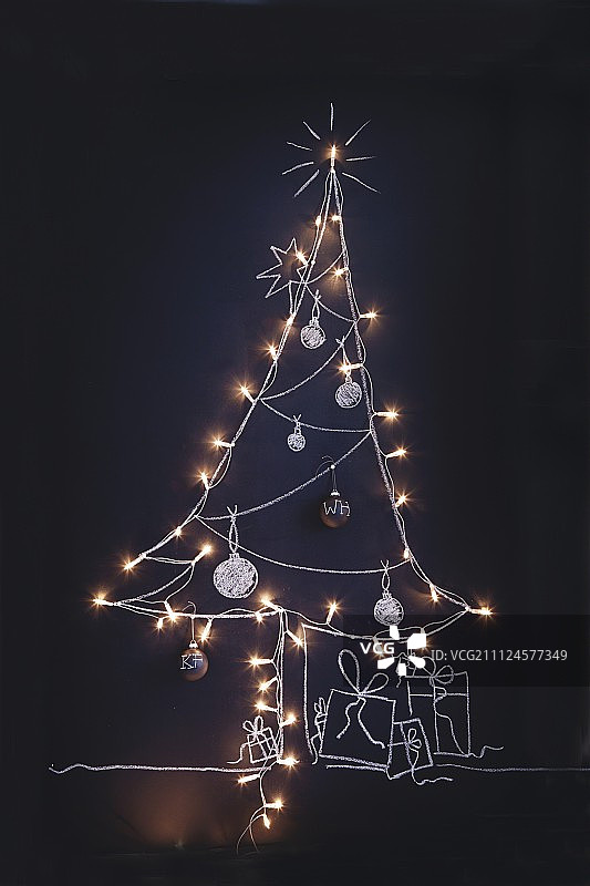 用粉笔在黑板上画的圣诞树，上面挂满了童话灯和小装饰品图片素材
