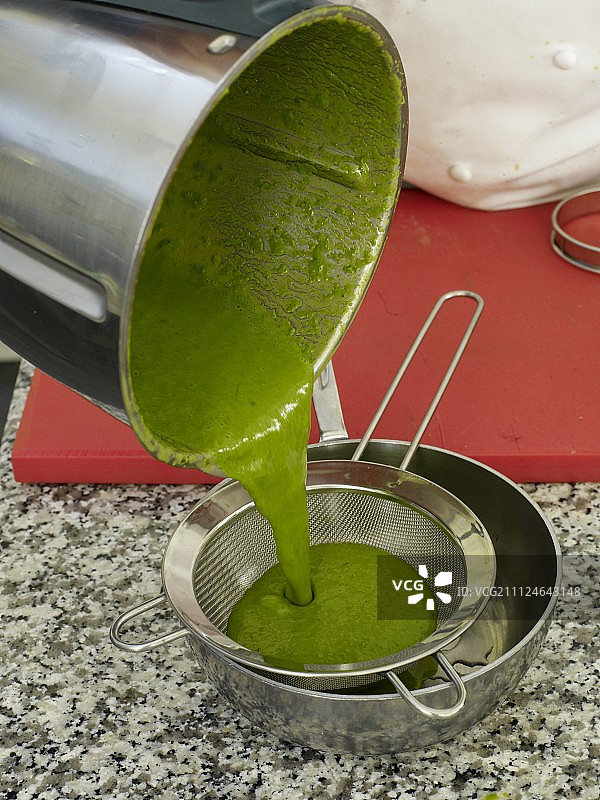 在平底锅中用滤网过滤绿色酱汁图片素材