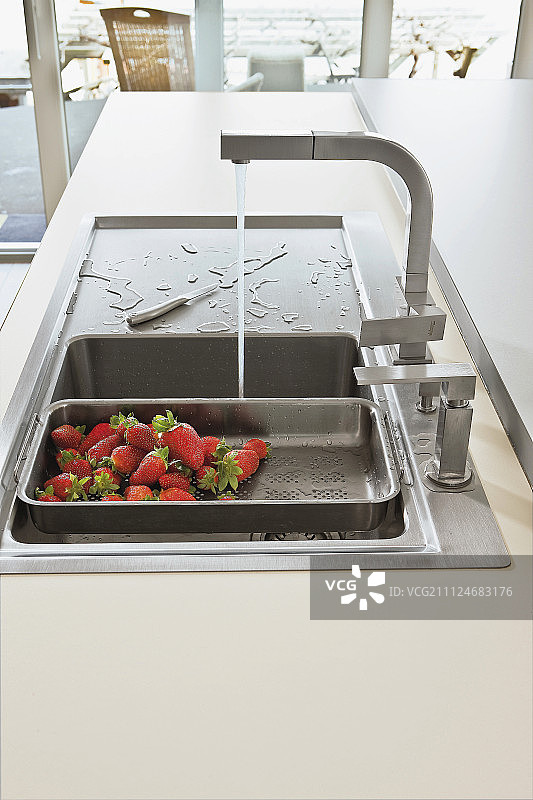 筛子里的新鲜草莓在水槽里清洗图片素材