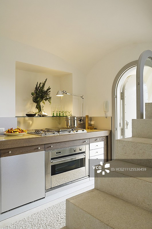 通过现代化的厨房柜台和照明壁龛的楼梯可以看到图片素材
