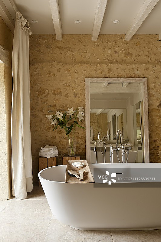 独立浴缸与木架和镜子靠在石墙浴室图片素材