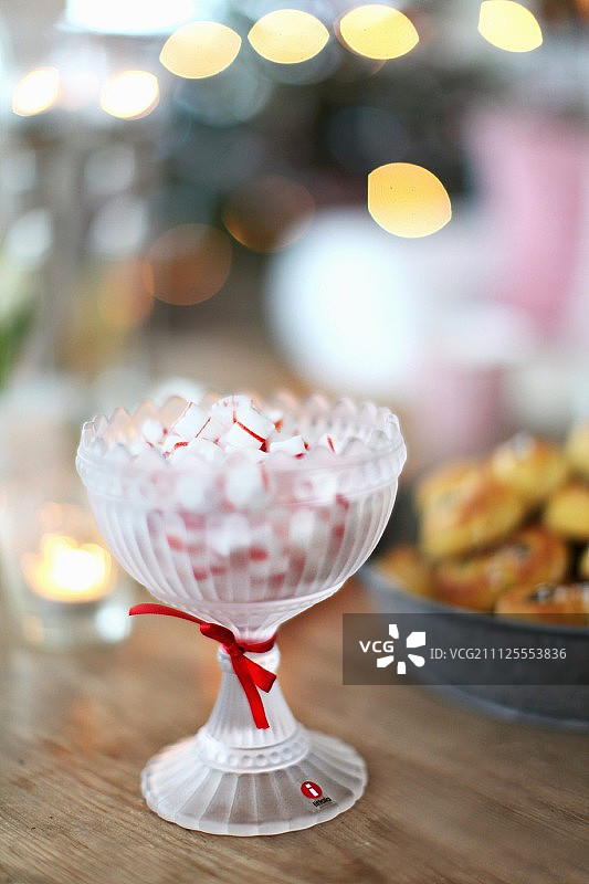 糖果装在复古的玻璃碗里，红丝带放在木桌上图片素材
