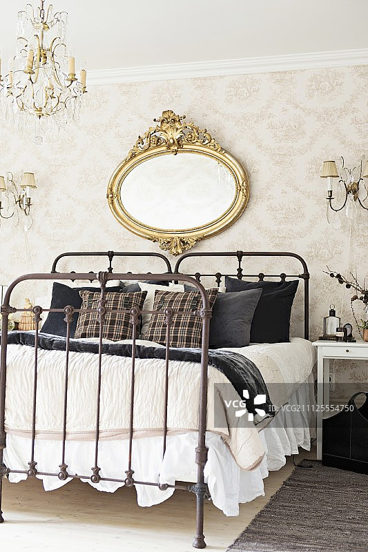 两张老式的双人床，上面有锻铁镜框，墙上挂着古董椭圆形的镀金镜框图片素材