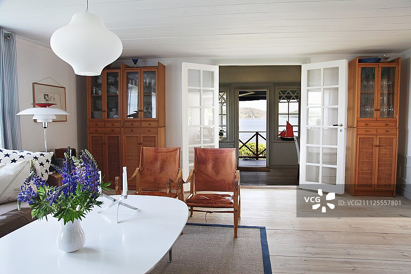 在宽敞的瑞典木屋里，白色的花瓶，椭圆形的桌子和古典的扶手椅图片素材