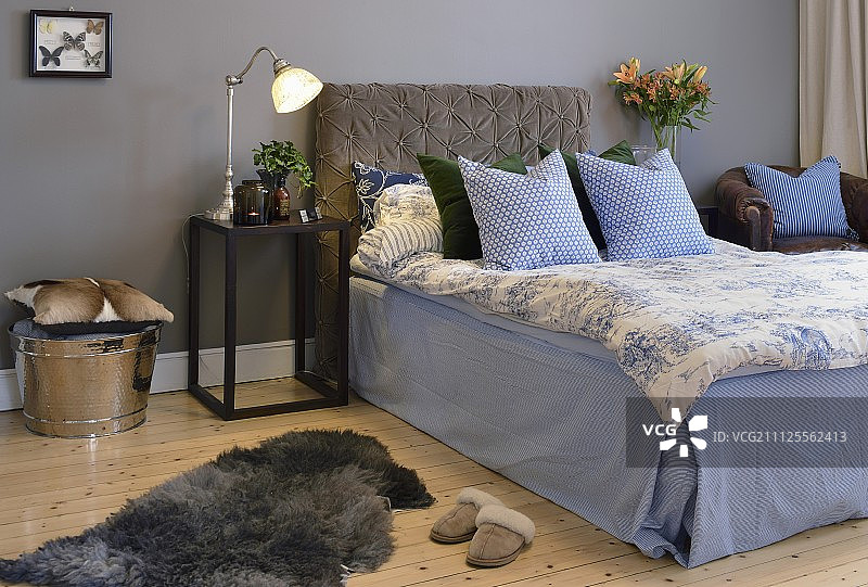 床上装有软垫床头板，蓝色和白色的亚麻布床衬着灰色的墙壁图片素材
