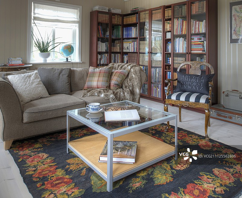 茶几上有花地毯，沙发和古董椅子，前面是l形的玻璃书柜图片素材