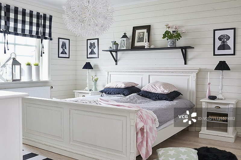 在质朴的卧室里，白色的古色古香的木床放在黑色的木墙架上，床头柜上放着台灯图片素材