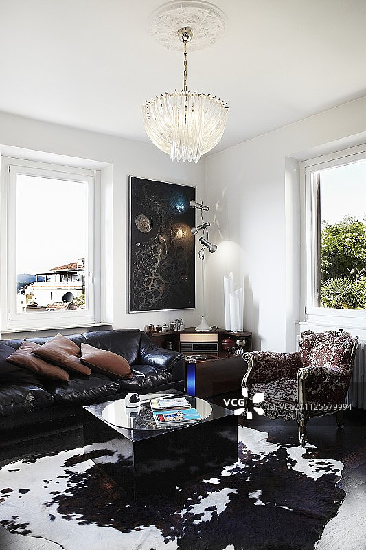 古典皮沙发上方的水晶吊灯，牛皮地毯上的立方体咖啡桌和巴洛克扶手椅图片素材