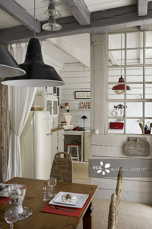 木质餐桌下的吊灯，在前面的厨房隔断玻璃格图片素材