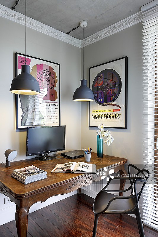 现代的黑色塑料椅子在古董桌上，吊灯在房间的角落，浅灰色的墙壁和白色的灰泥装饰图片素材