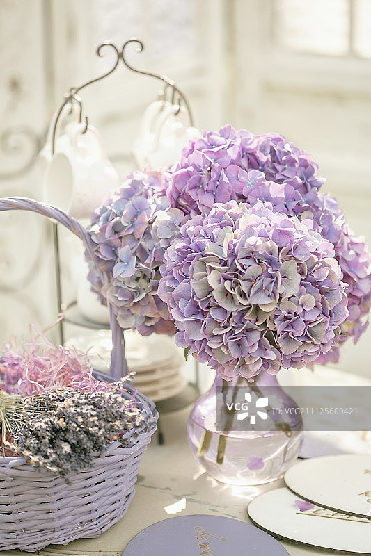 一束紫色的绣球花放在玻璃花瓶里，旁边是一篮干薰衣草图片素材