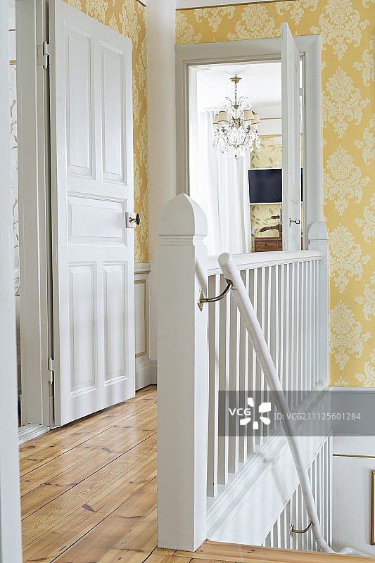 质朴的楼梯间，白色的木制楼梯和华丽的黄色墙纸图片素材