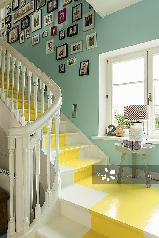 白色的木楼梯与黄色的中央条纹在楼梯井与绿松石漆墙壁和画廊的图片图片素材
