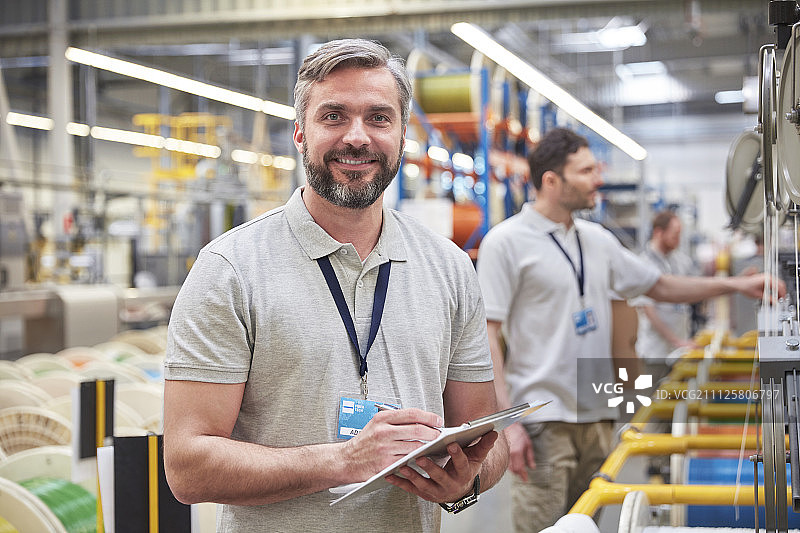 肖像微笑，自信的男性主管与剪贴板在光纤工厂图片素材
