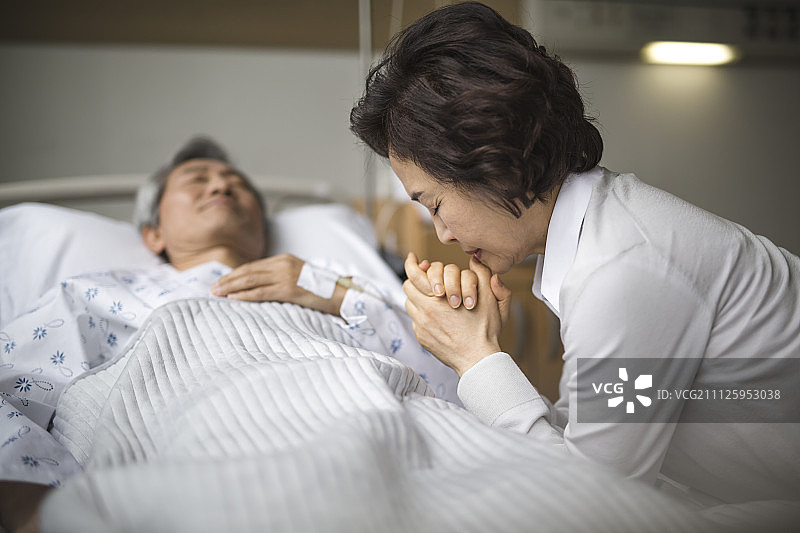 老妇人在病床上为丈夫祈祷图片素材
