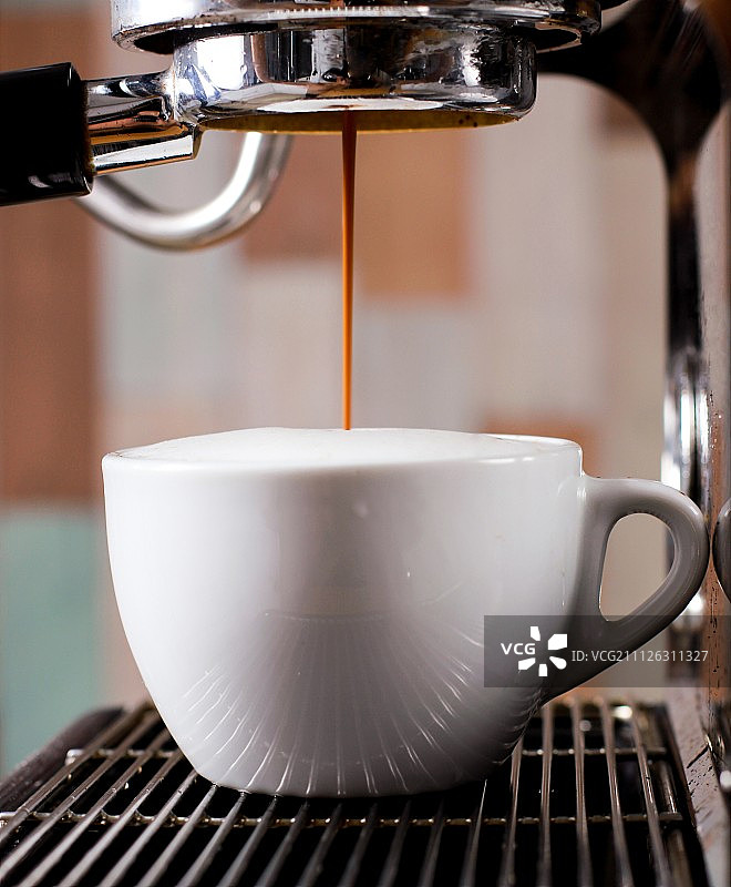 咖啡机上的咖啡杯。图片素材