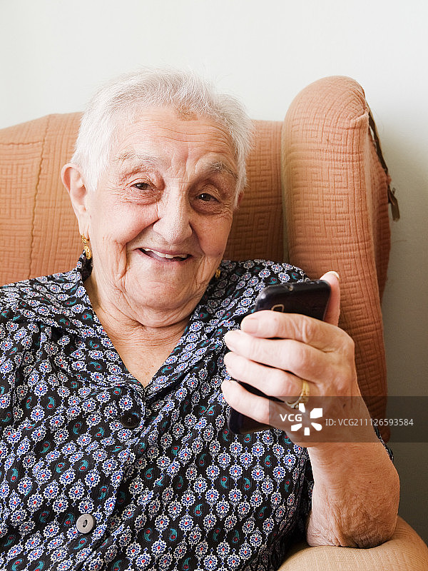 拿着智能手机，面带微笑的老太太图片素材