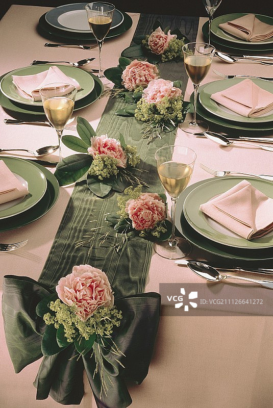 绿色盘子的餐桌布置;粉红色的花朵图片素材