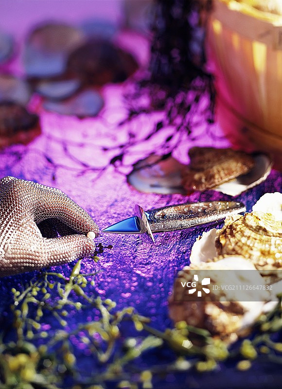 牡蛎，牡蛎刀，手套和珍珠在紫罗兰背景图片素材