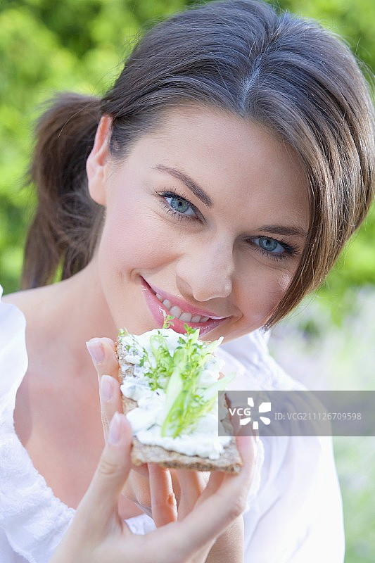年轻女子吃脆饼配白软干酪和黄瓜图片素材