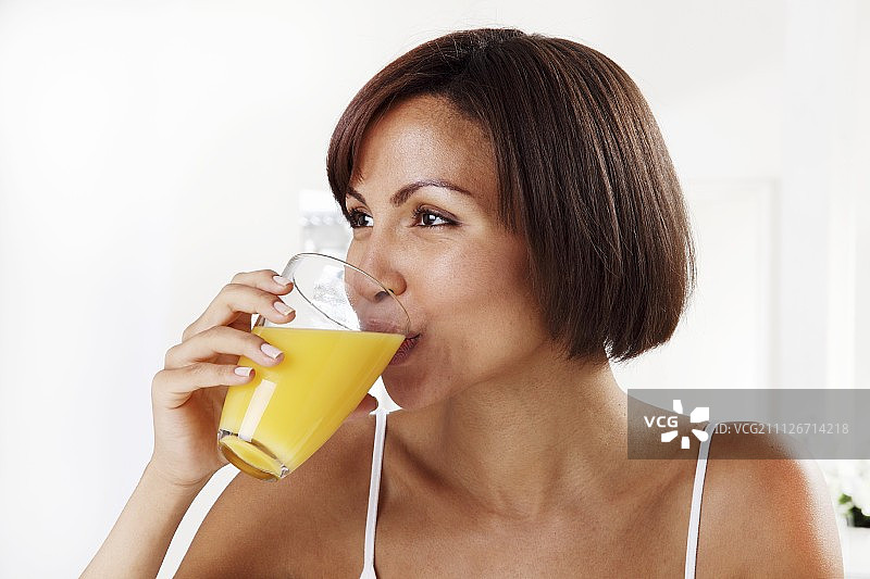 喝橙汁的年轻女子，特写图片素材